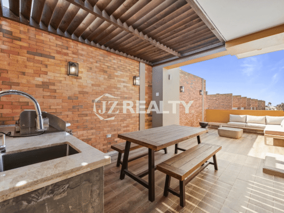 Large third-floor terrace with built-in outdoor kitchen/grill area, wooden picnic table, and outdoor sectional sofa, offering an excellent entertaining space in Porta al Sole Unit 15.