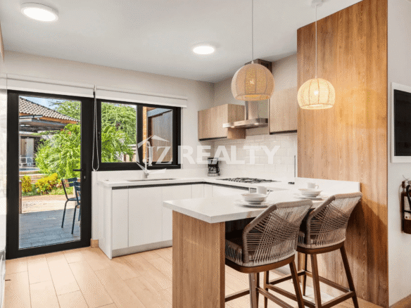 Corner view of the bright kitchen in Porta al Sole Unit 18, showing white subway tile backsplash, gas cooktop, breakfast bar with barstools, and a glass door leading to the outdoor space.