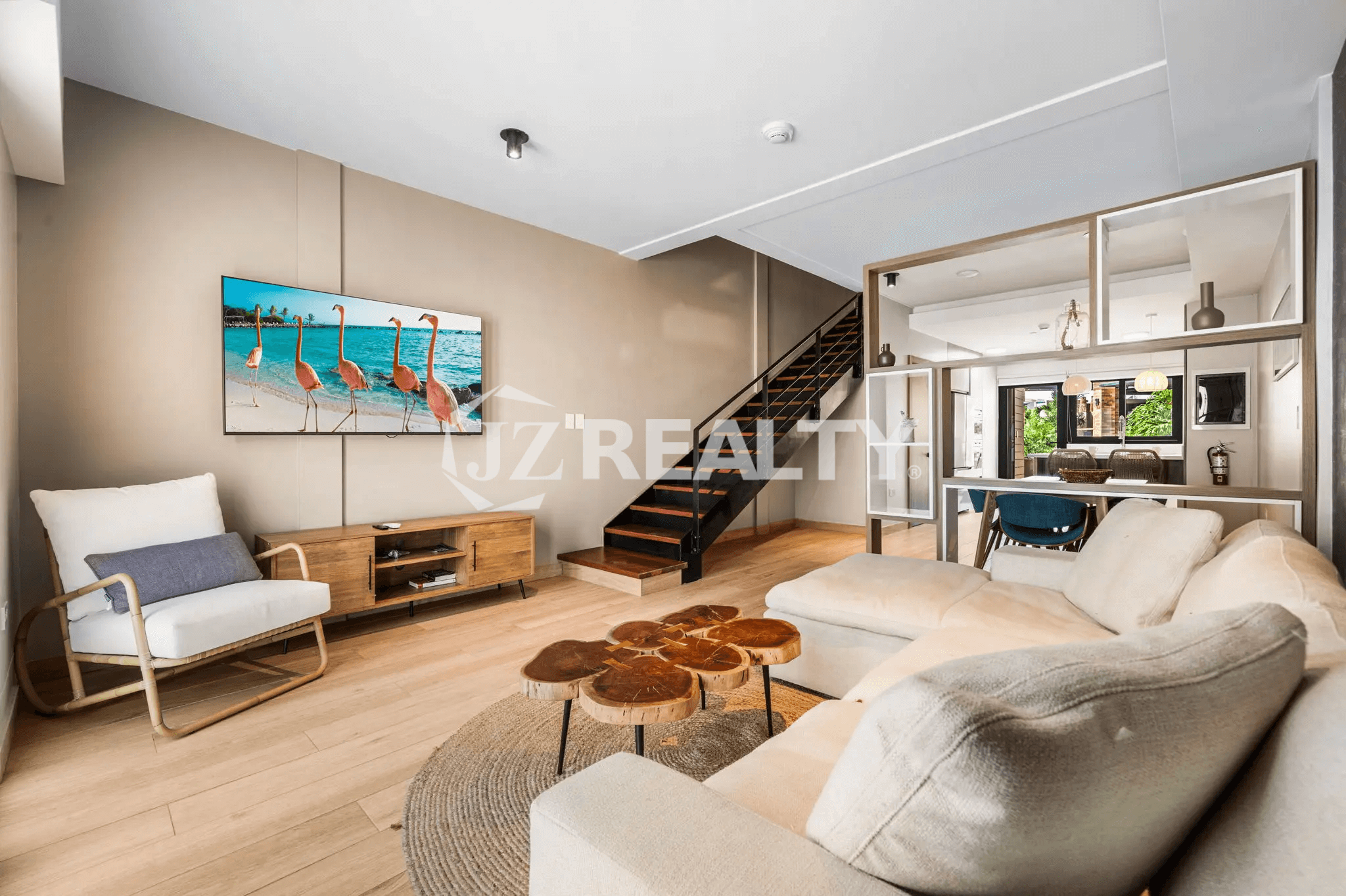 Contemporary living room in Porta al Sole Unit 18 with a wall-mounted TV, media console, comfortable accent chair, and sectional sofa, showing the open concept to the dining and kitchen areas.