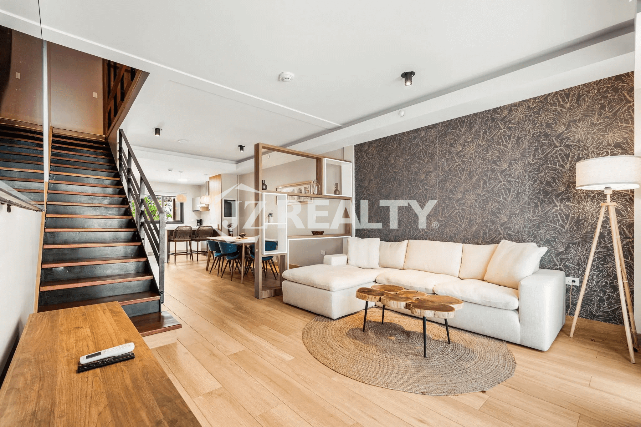Luxurious living room in Porta al Sole Unit 18 with large sectional sofa, wood coffee tables, textured accent wall, light wood floor, and open staircase leading to upper floors.