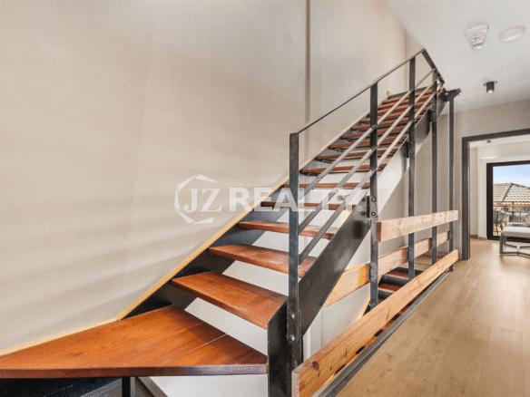 Interior shot of the modern open-tread staircase in Porta al Sole Unit 18, featuring wood steps and black metal railings leading to the upper floor hallway.