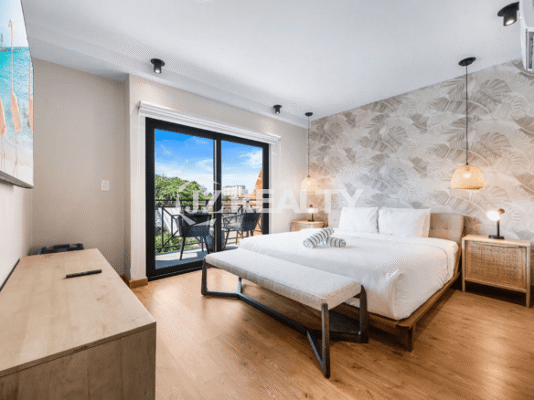 Primary bedroom in Porta al Sole Unit 18 with a bed, bench, nightstands, and a tropical-patterned accent wallpaper wall behind the headboard.