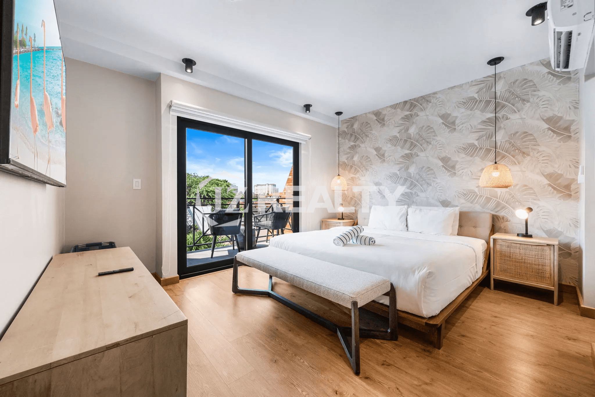Primary bedroom in Porta al Sole Unit 18 with a bed, bench, nightstands, and a tropical-patterned accent wallpaper wall behind the headboard.