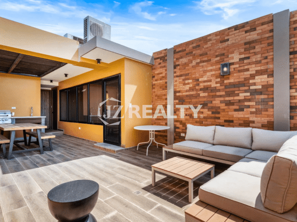 Spacious rooftop terrace at Porta al Sole Unit 18 featuring an outdoor kitchen/grill area, a large sectional seating area with cushions, and sun-drenched wood-look tile flooring.