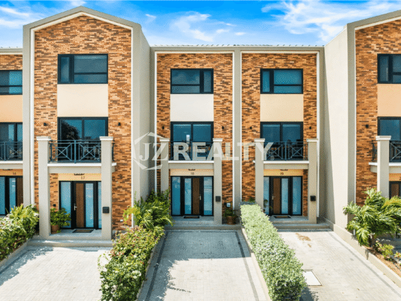 Exterior view of the Porta al Sole townhouses, showing the modern brick and stucco facade, with Unit 18 visible in the center, and landscaped entryway.
