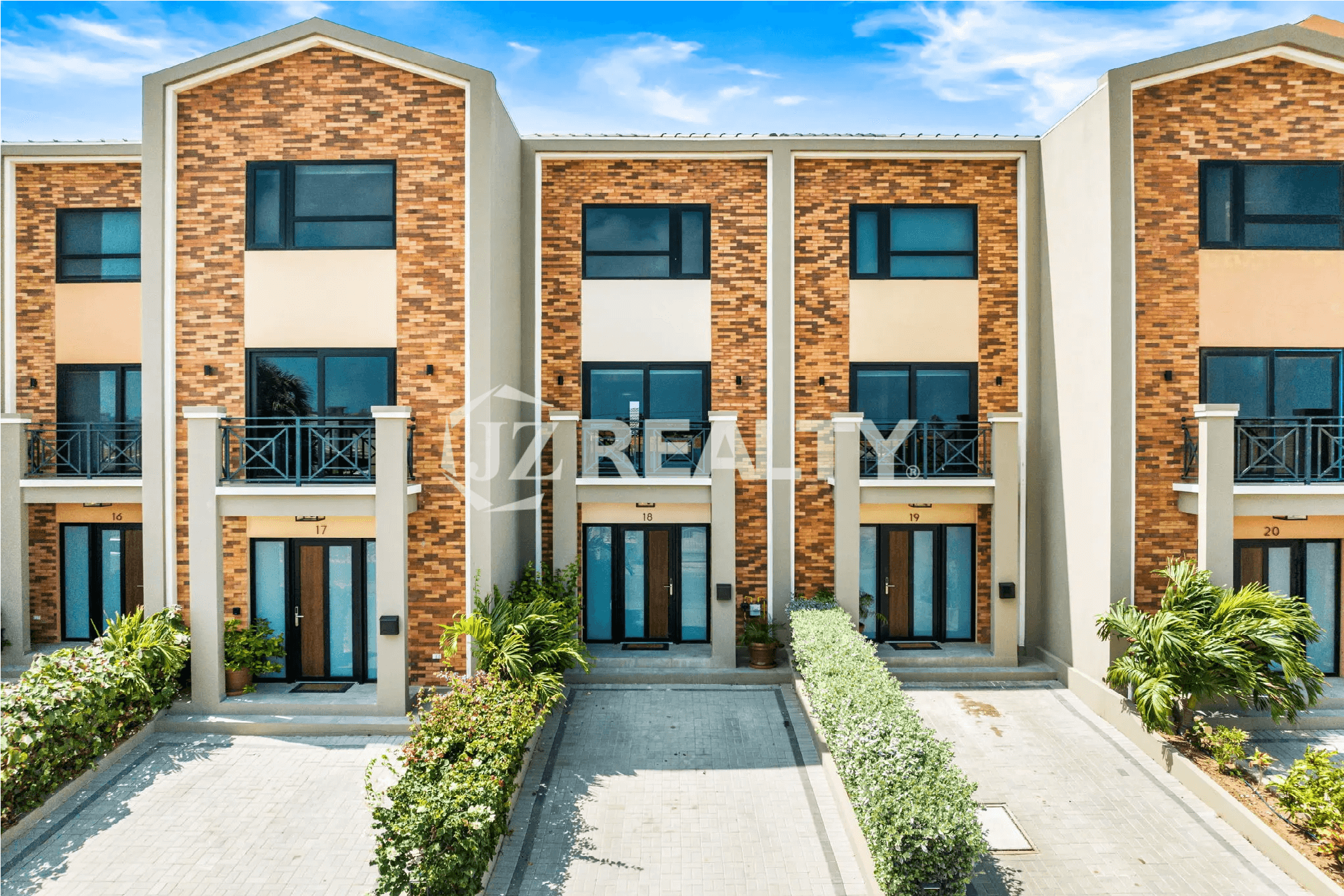 Exterior view of the Porta al Sole townhouses, showing the modern brick and stucco facade, with Unit 18 visible in the center, and landscaped entryway.