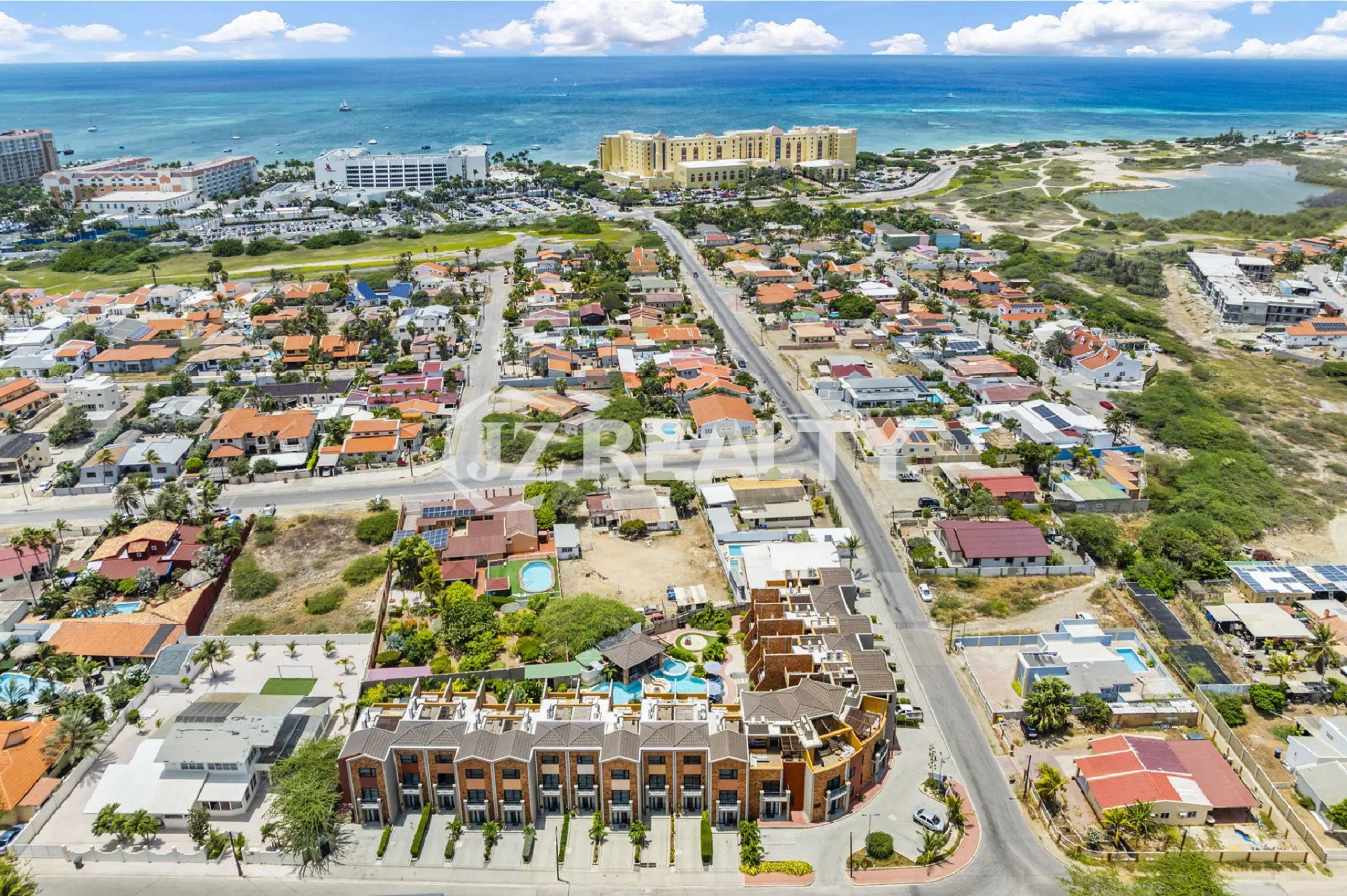 Wide aerial view of the Porta al Sole complex and surrounding neighborhood, showing its proximity to the ocean and Palm Beach hotels.
