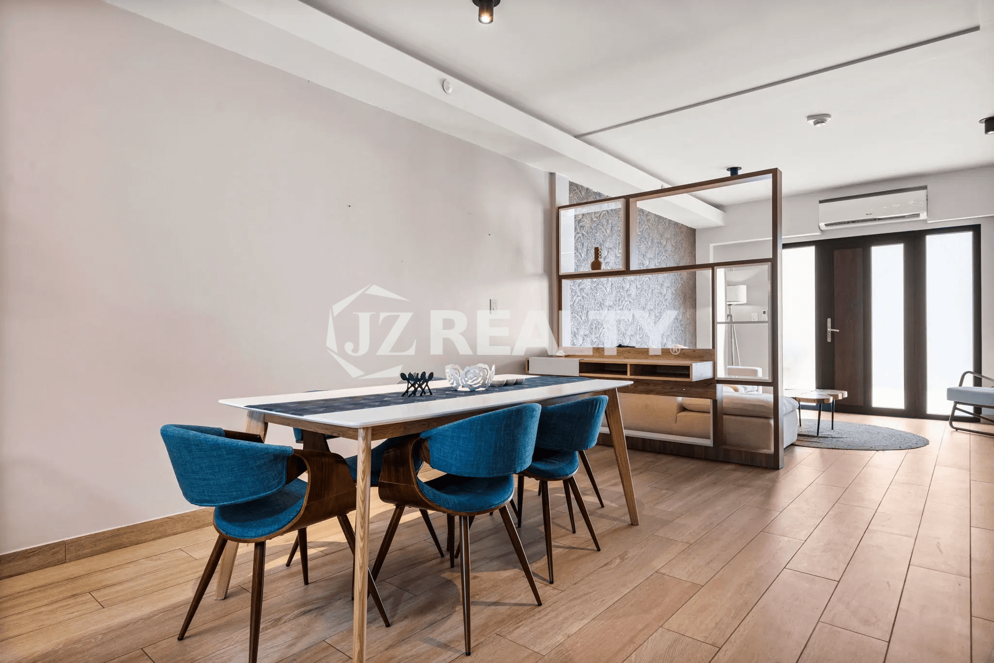 Dining space in Porta al Sole Unit 8 featuring a long table with blue upholstered chairs and a view into the living area.