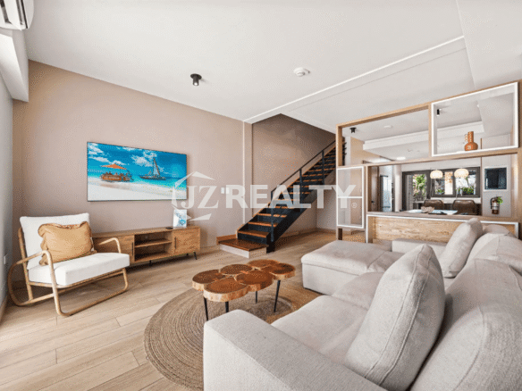 Bright living room in Porta al Sole Unit 8 with a large sectional sofa, coffee table, entertainment center, and stairs leading to the upper floors.
