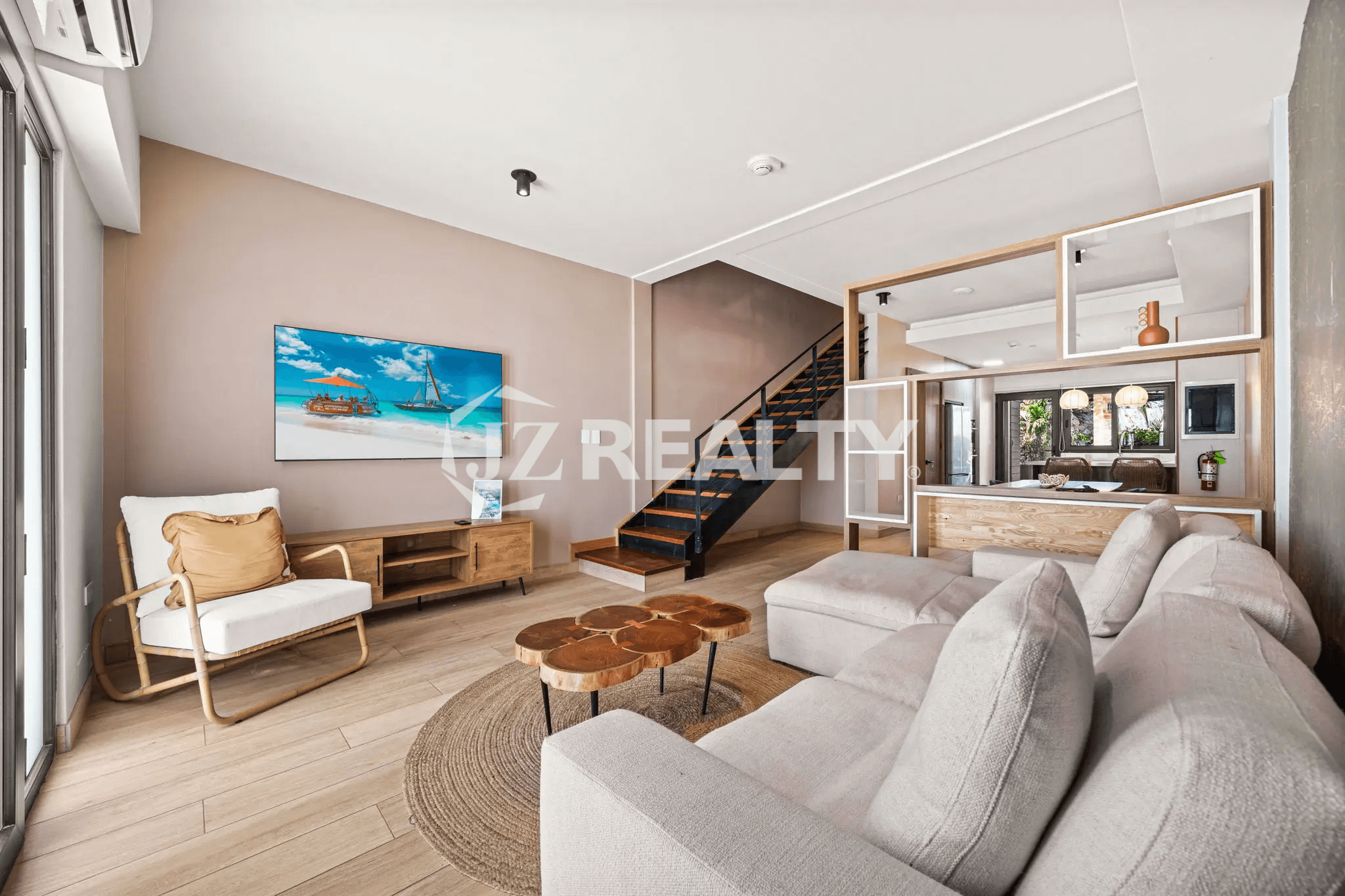 Bright living room in Porta al Sole Unit 8 with a large sectional sofa, coffee table, entertainment center, and stairs leading to the upper floors.