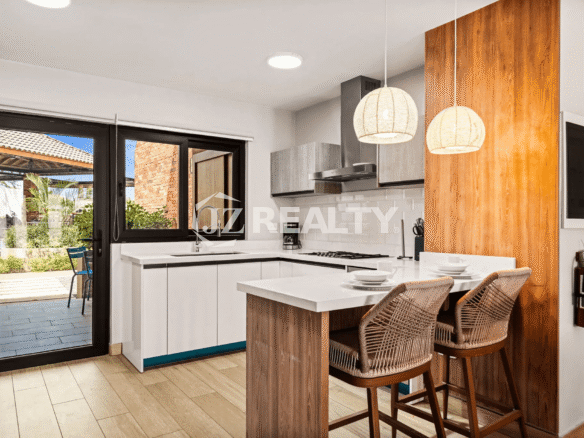 Modern L-shaped kitchen in Porta al Sole Unit 8 with white cabinets, a breakfast bar, stainless steel appliances, and a sliding door to the patio.