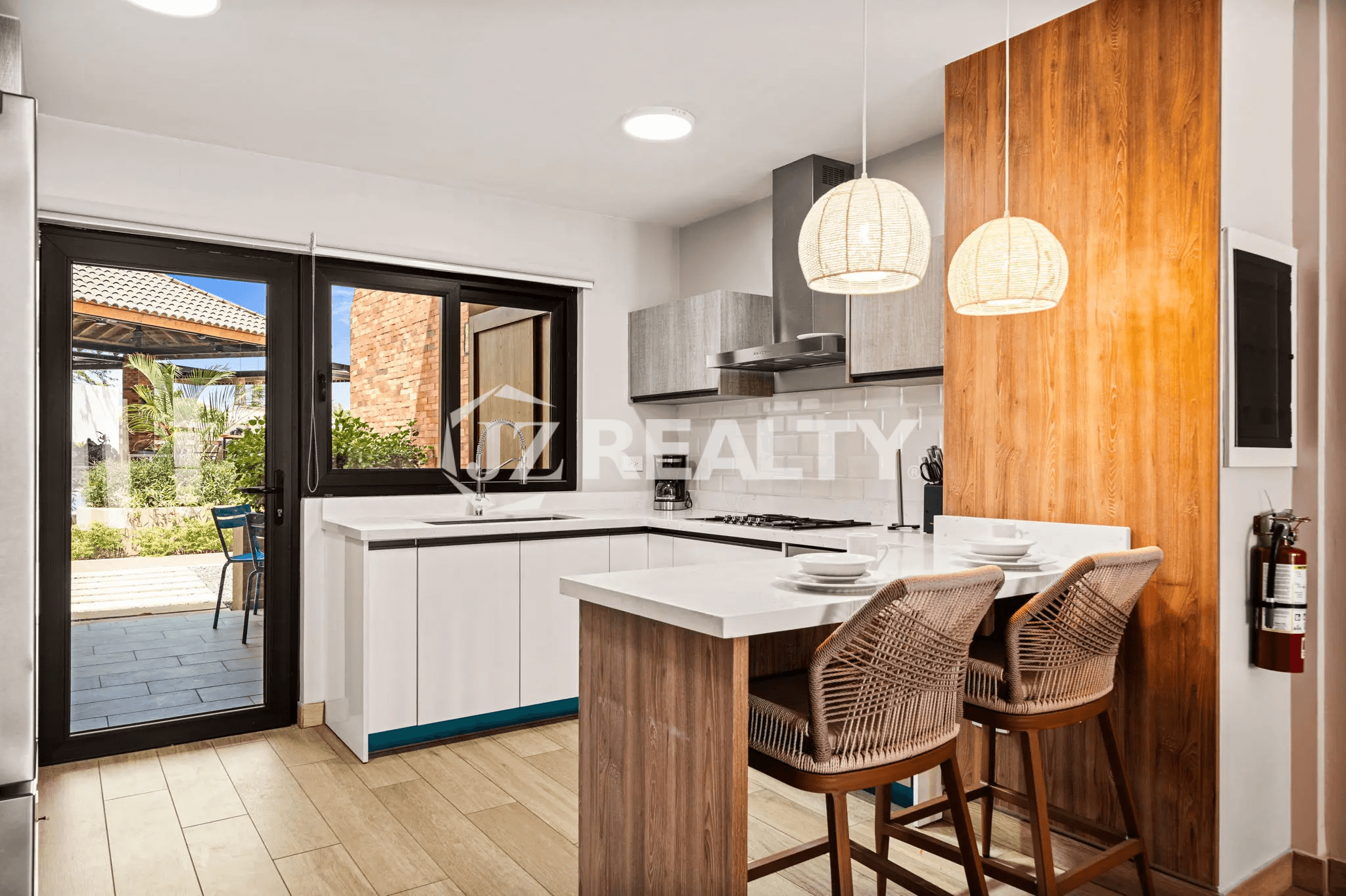 Modern L-shaped kitchen in Porta al Sole Unit 8 with white cabinets, a breakfast bar, stainless steel appliances, and a sliding door to the patio.