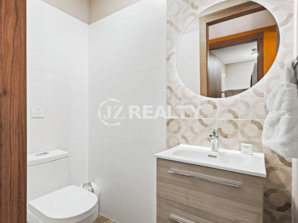 Powder room/half bath in Porta al Sole Unit 8 with a toilet, vanity, and a round mirrored wall design.