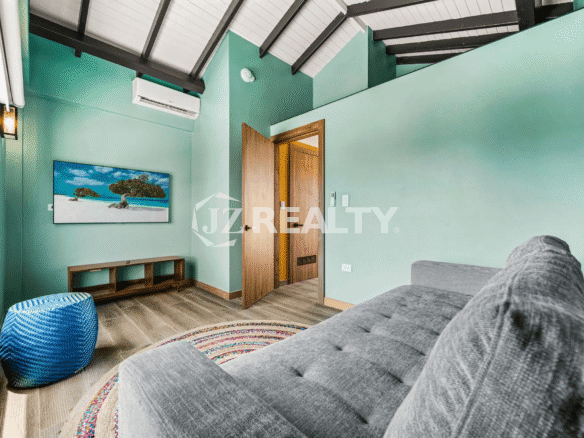 Cozy sitting room on Floor 3 of Porta al Sole Unit 8 with a vaulted ceiling, lounge chaise, bright turquoise walls, and a mounted TV.