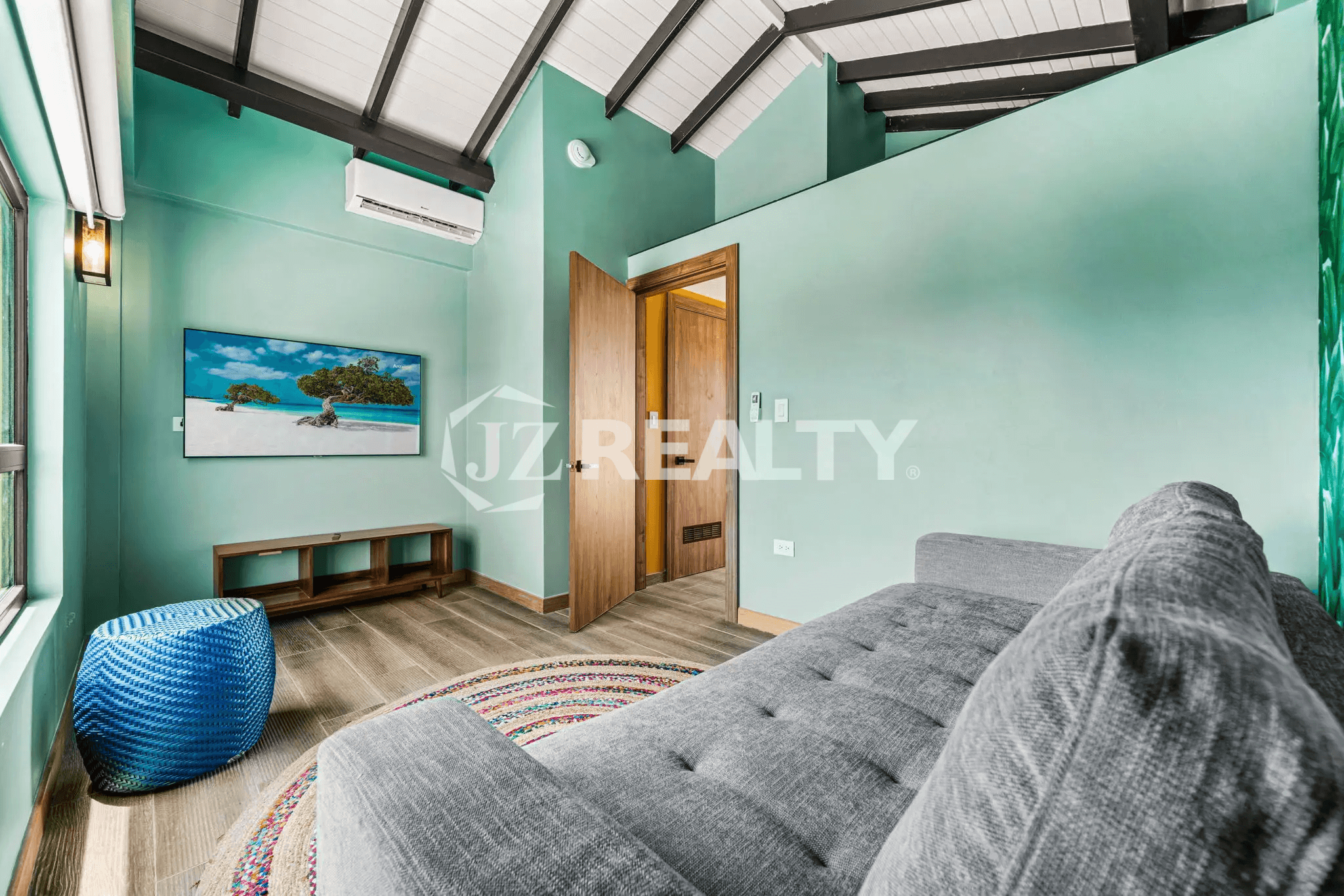 Cozy sitting room on Floor 3 of Porta al Sole Unit 8 with a vaulted ceiling, lounge chaise, bright turquoise walls, and a mounted TV.