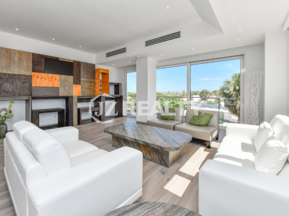 Spacious living room in Coral Shell Condo 2E, featuring elegant white sofas, custom wooden accent walls, and large windows with natural light.
