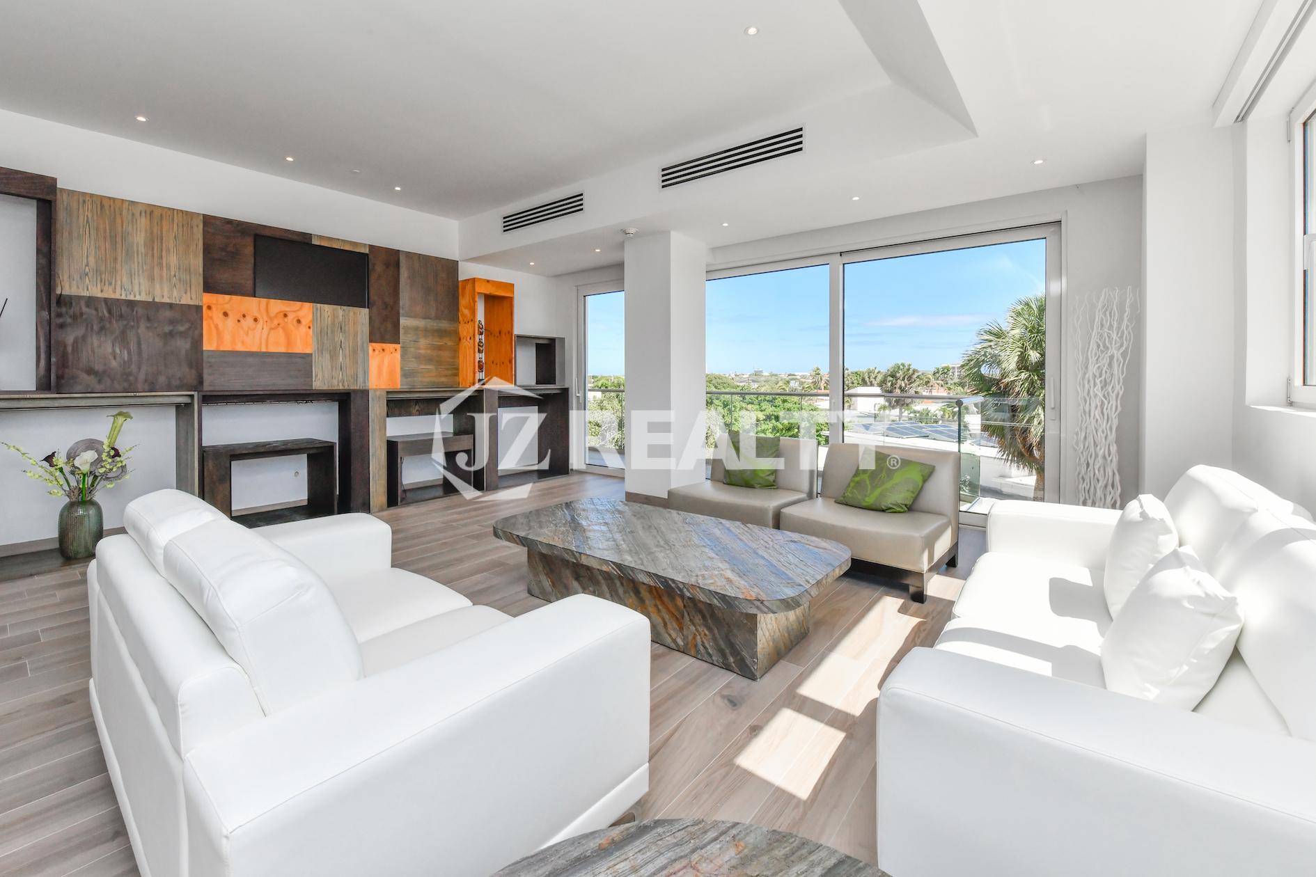 Spacious living room in Coral Shell Condo 2E, featuring elegant white sofas, custom wooden accent walls, and large windows with natural light.