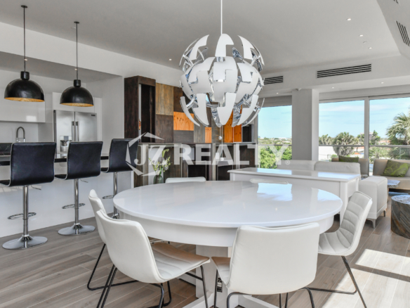 Stylish dining area at Coral Shell Condo 2E in Oranjestad, Aruba, featuring a sleek white round table, modern chairs, and a statement designer chandelier.