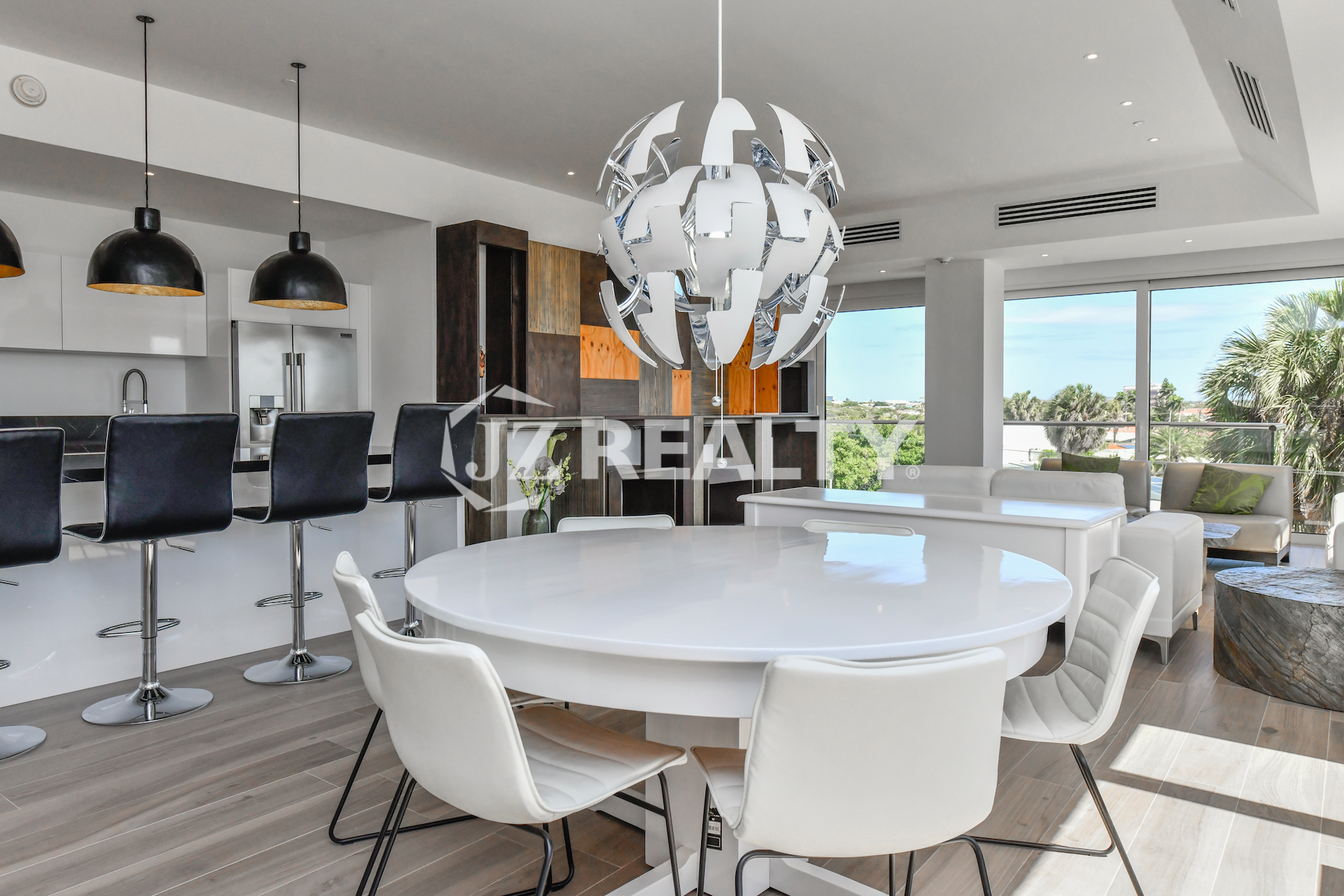 Stylish dining area at Coral Shell Condo 2E in Oranjestad, Aruba, featuring a sleek white round table, modern chairs, and a statement designer chandelier.