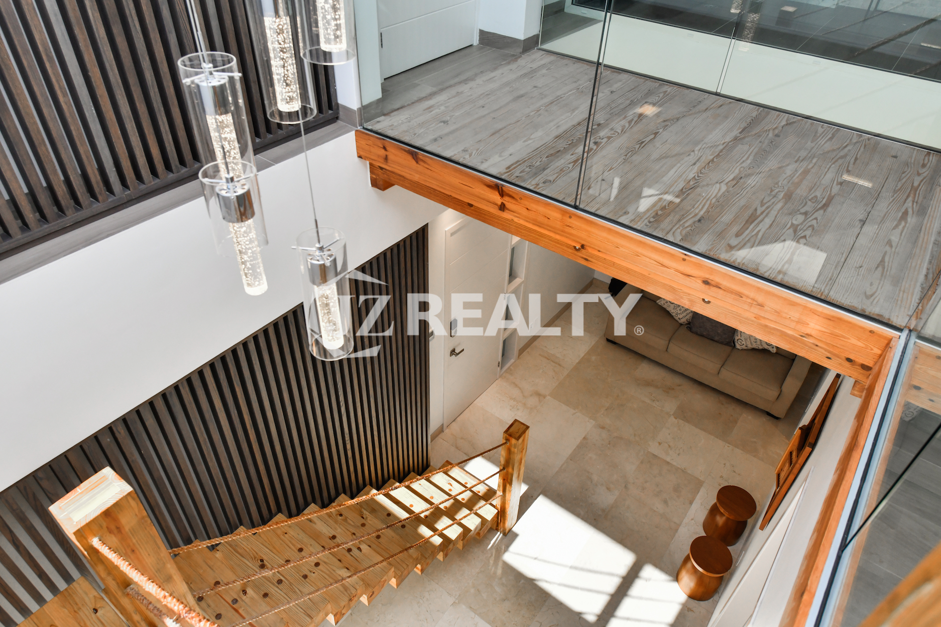Modern loft-style staircase in Coral Shell Condo 1E, featuring wooden steps, glass railings, and high ceilings