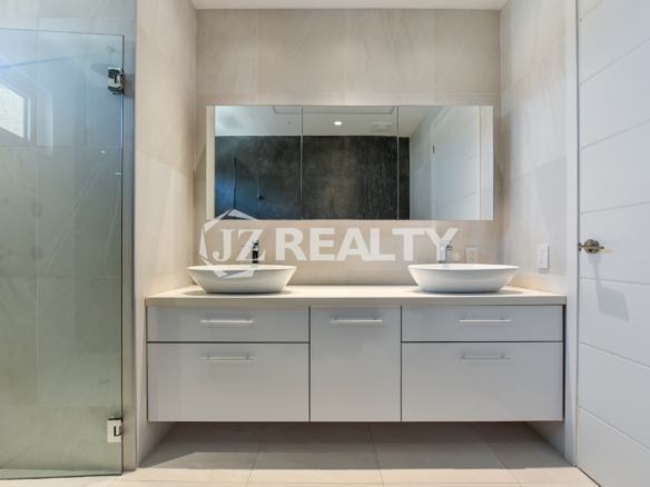 Coral Shell Condo 1E & 2E luxury loft bathroom with a double vanity, large mirrors, and glass shower.
