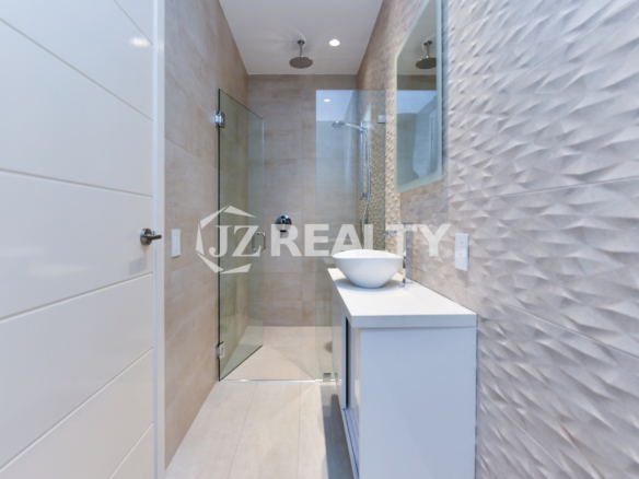 Coral Shell Condo 1E & 2E luxury loft walk-in shower with a rainfall showerhead and glass enclosure.