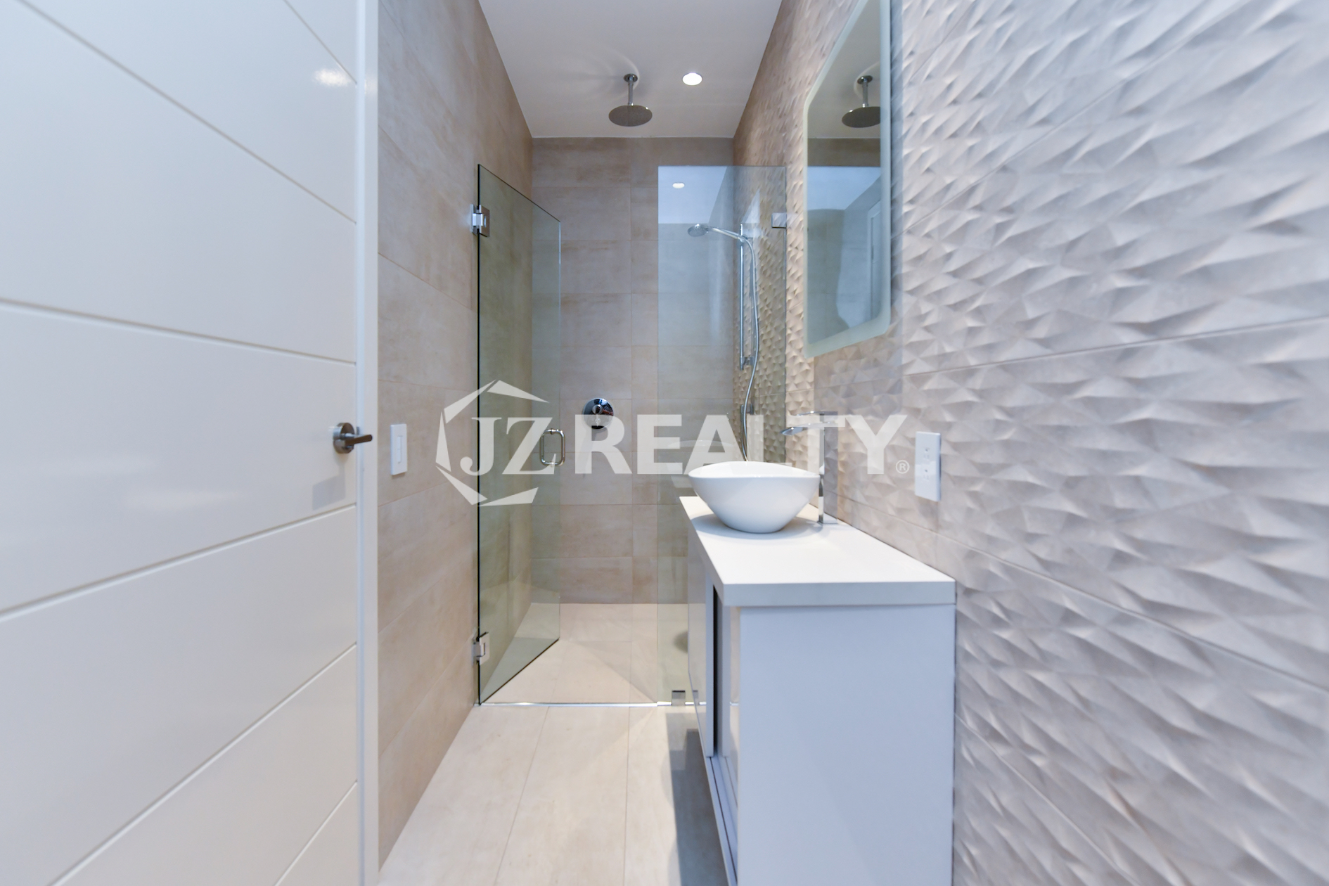 Coral Shell Condo 1E & 2E luxury loft walk-in shower with a rainfall showerhead and glass enclosure.