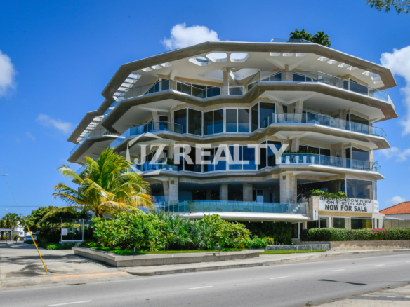 The modern and architecturally unique Coral Shell Condo in Aruba, captured from a street view, showcasing its luxurious beachfront design.