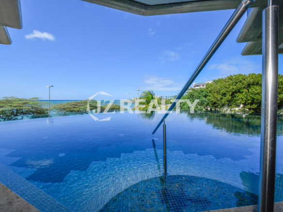 A luxurious infinity pool at Coral Shell Condo in Aruba, overlooking the turquoise waters of the Caribbean, offering an unmatched relaxation
