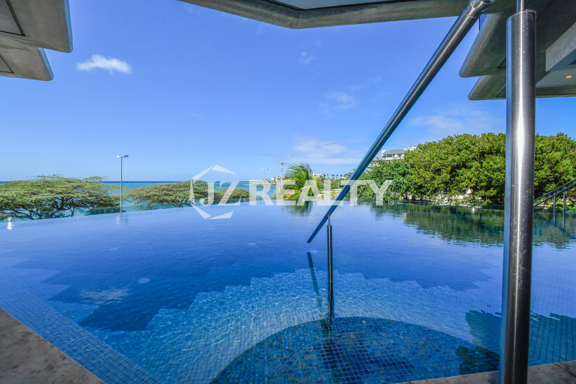 A luxurious infinity pool at Coral Shell Condo in Aruba, overlooking the turquoise waters of the Caribbean, offering an unmatched relaxation