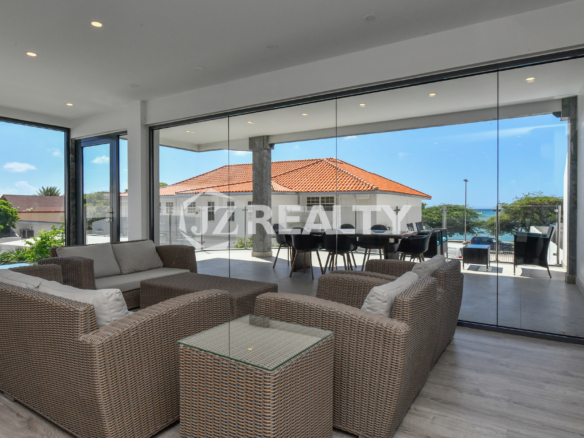 Indoor-outdoor living area with ocean-view terrace in Condo 1H, Coral Shell Condominium, Aruba.