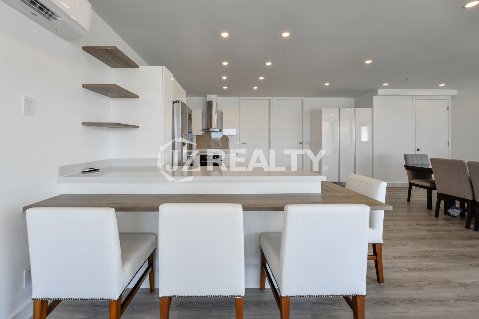 Modern living room with a flat-screen TV and open kitchen in Condo 1H, Coral Shell Condominium, Aruba.