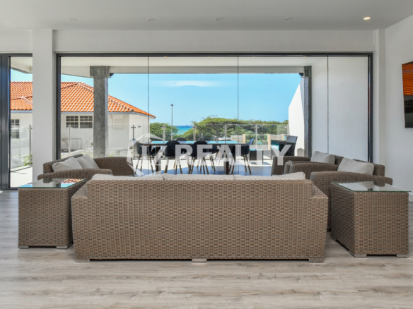 Spacious living room with direct access to an ocean-view terrace in Condo 1H, Coral Shell Condominium, Aruba.