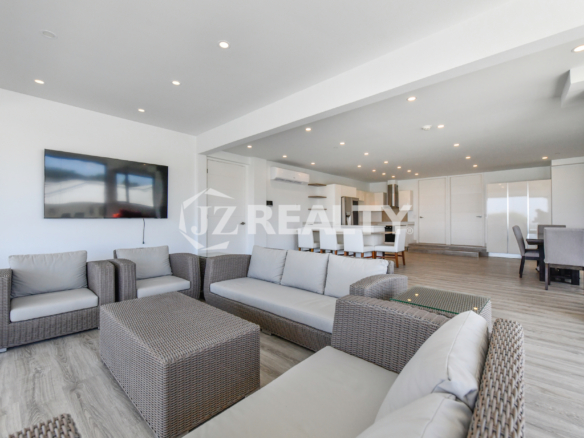 Modern living room with a flat-screen TV and open kitchen in Condo 1H, Coral Shell Condominium, Aruba.