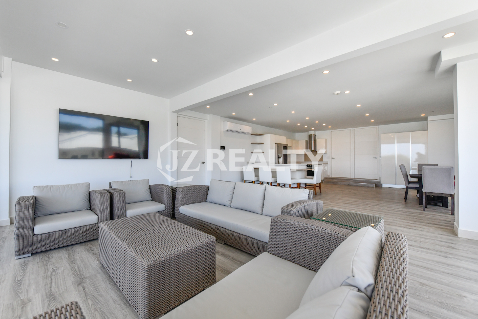 Modern living room with a flat-screen TV and open kitchen in Condo 1H, Coral Shell Condominium, Aruba.