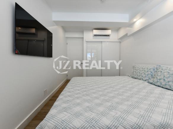 Stylish bedroom with built-in closet and wall-mounted TV at Coral Shell Condo 1H, Aruba.