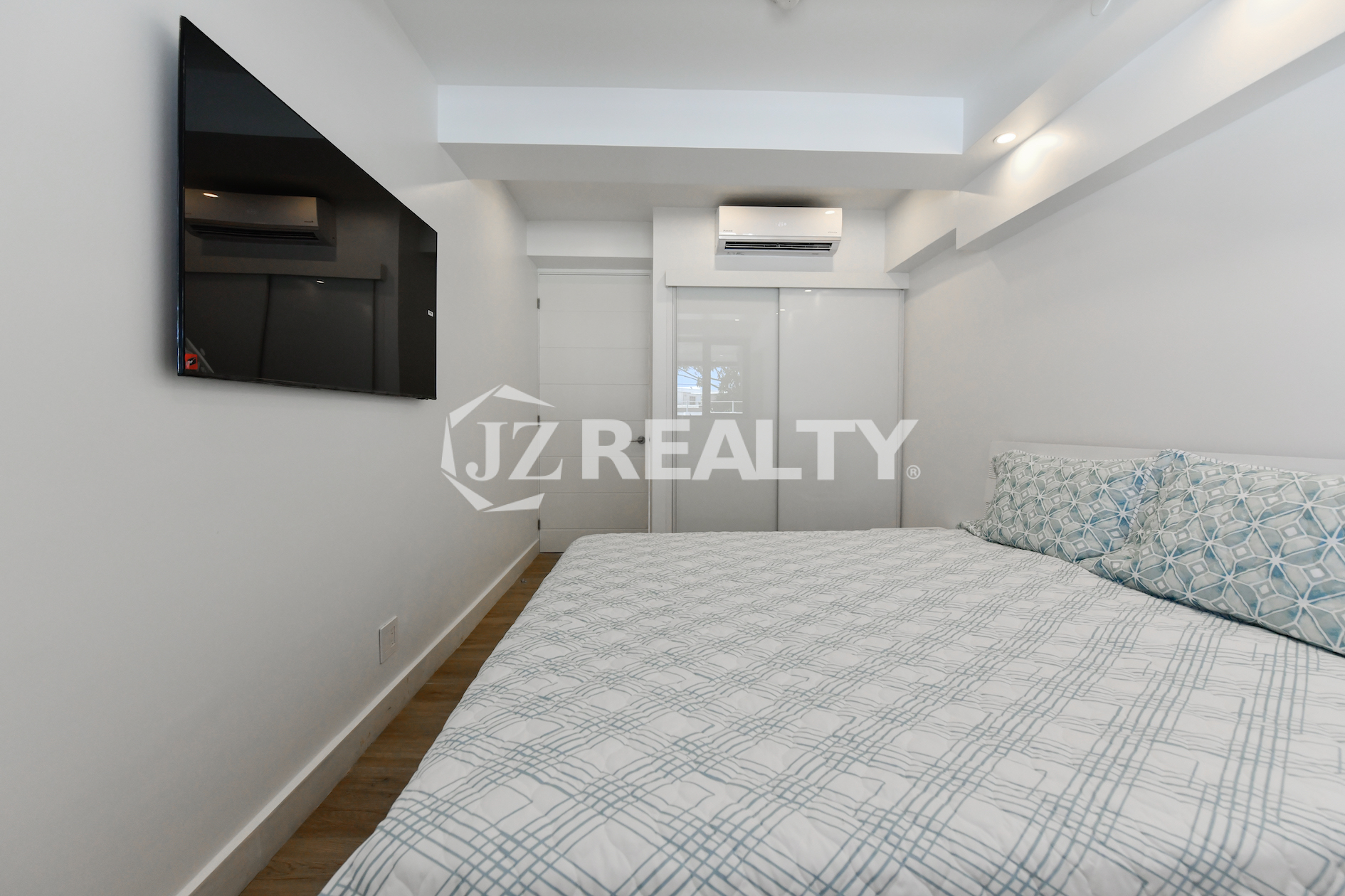 Stylish bedroom with built-in closet and wall-mounted TV at Coral Shell Condo 1H, Aruba.