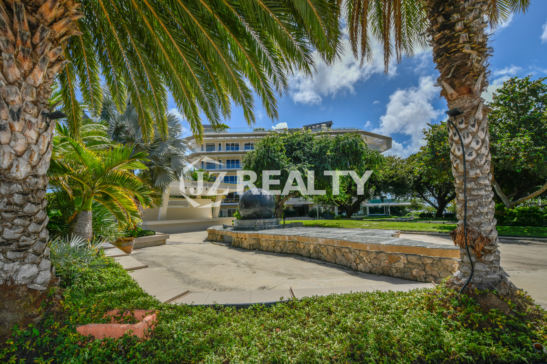The lush entrance of Coral Shell Condo in Oranjestad, Aruba, featuring a tropical park-like setting.