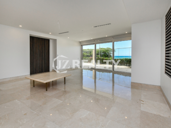 Luxurious living room with floor-to-ceiling windows and direct ocean views at Coral Shell Condo in Oranjestad, Aruba.