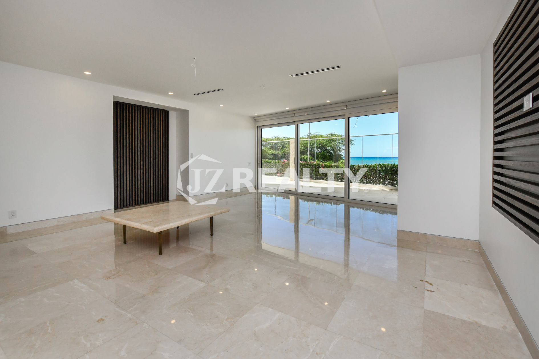 Luxurious living room with floor-to-ceiling windows and direct ocean views at Coral Shell Condo in Oranjestad, Aruba.