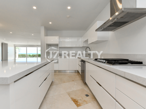 Spacious modern kitchen with white high-gloss cabinetry and ocean views at Coral Shell Condo in Oranjestad, Aruba.