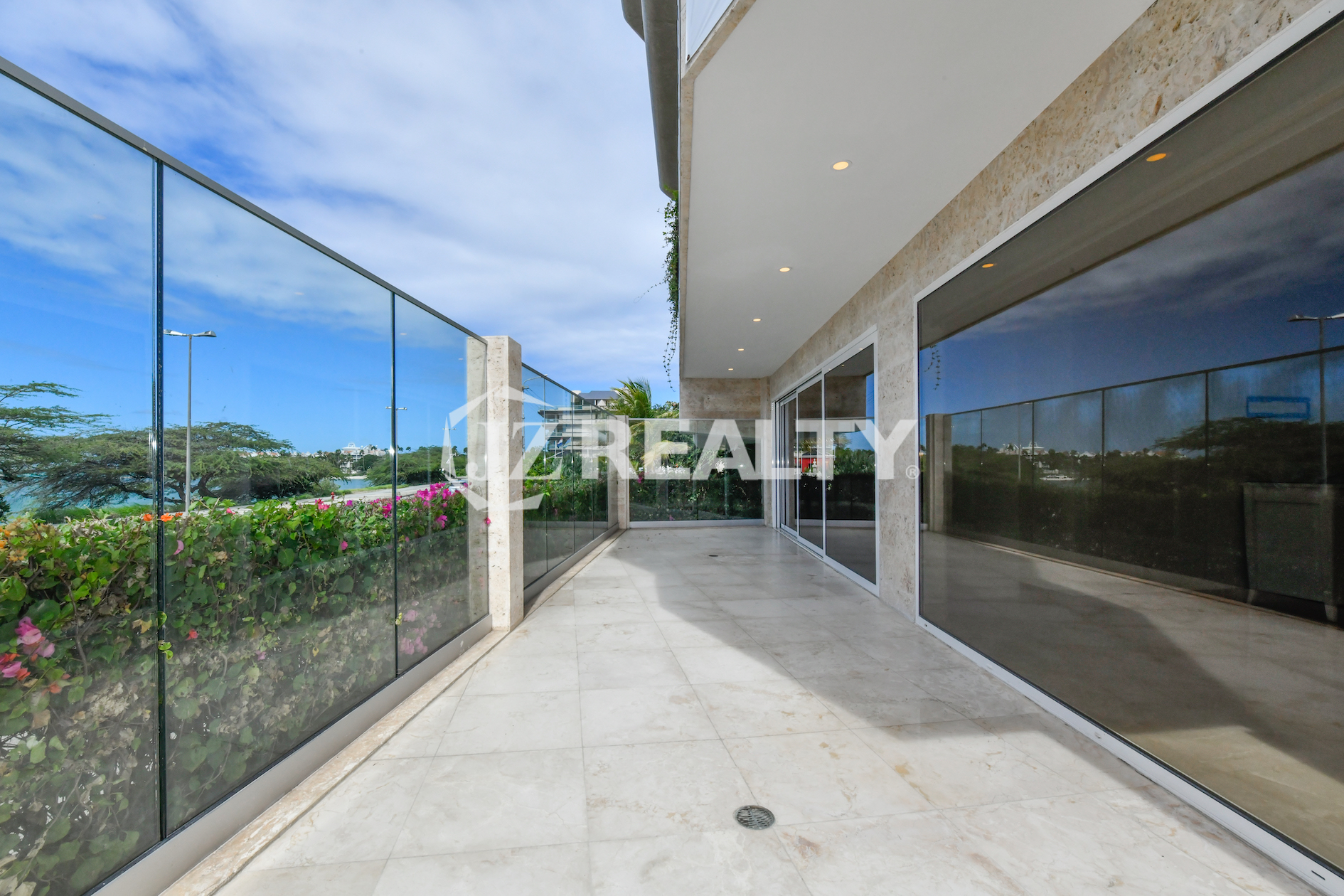 Private balcony with ocean views at Coral Shell Condo GF-C, featuring glass railings and marble flooring.