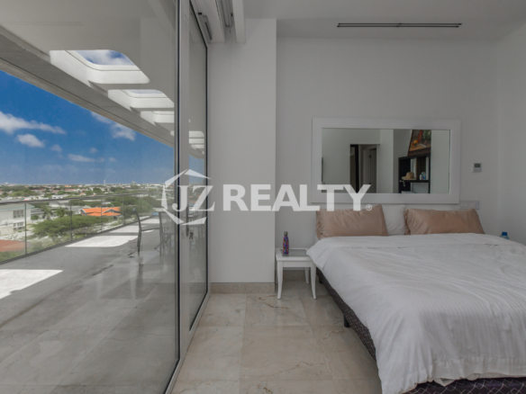 Luxury bedroom with floor-to-ceiling windows and island views at Coral Shell Penthouse B, Aruba.
