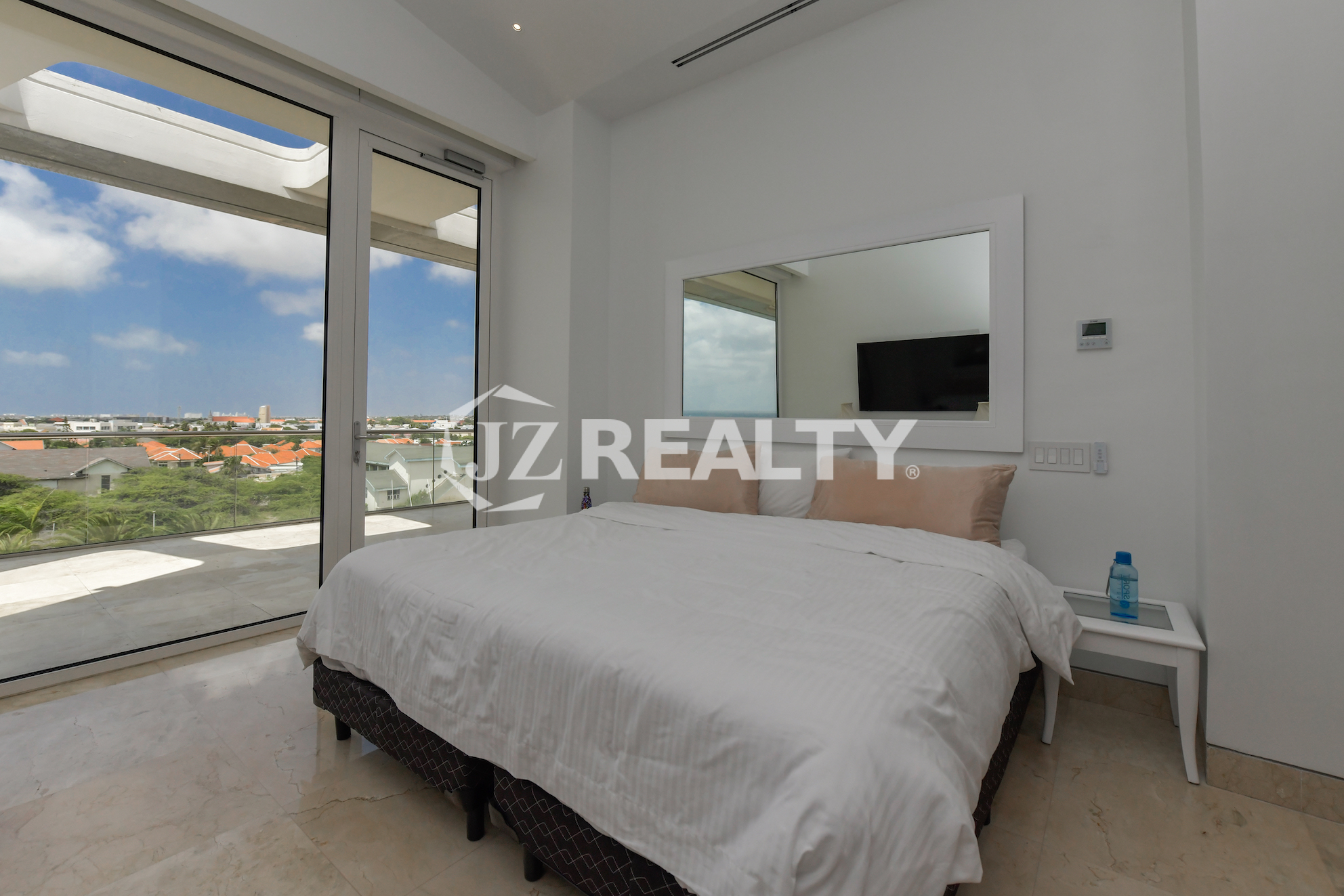 Luxurious bedroom with a spacious balcony and breathtaking ocean and city views at Coral Shell Penthouse B, Aruba.