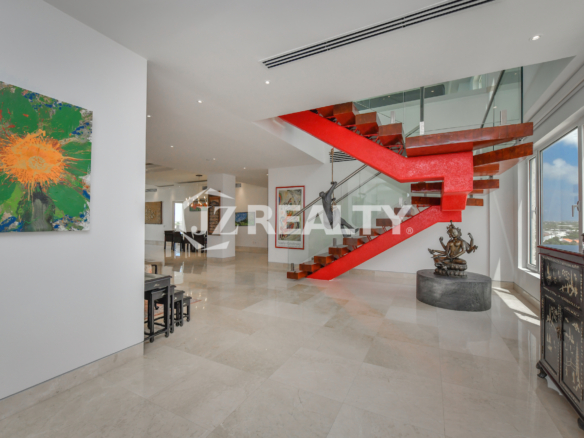 Elegant floating staircase with glass railings and a bold red accent at Coral Shell Penthouse B, Aruba.