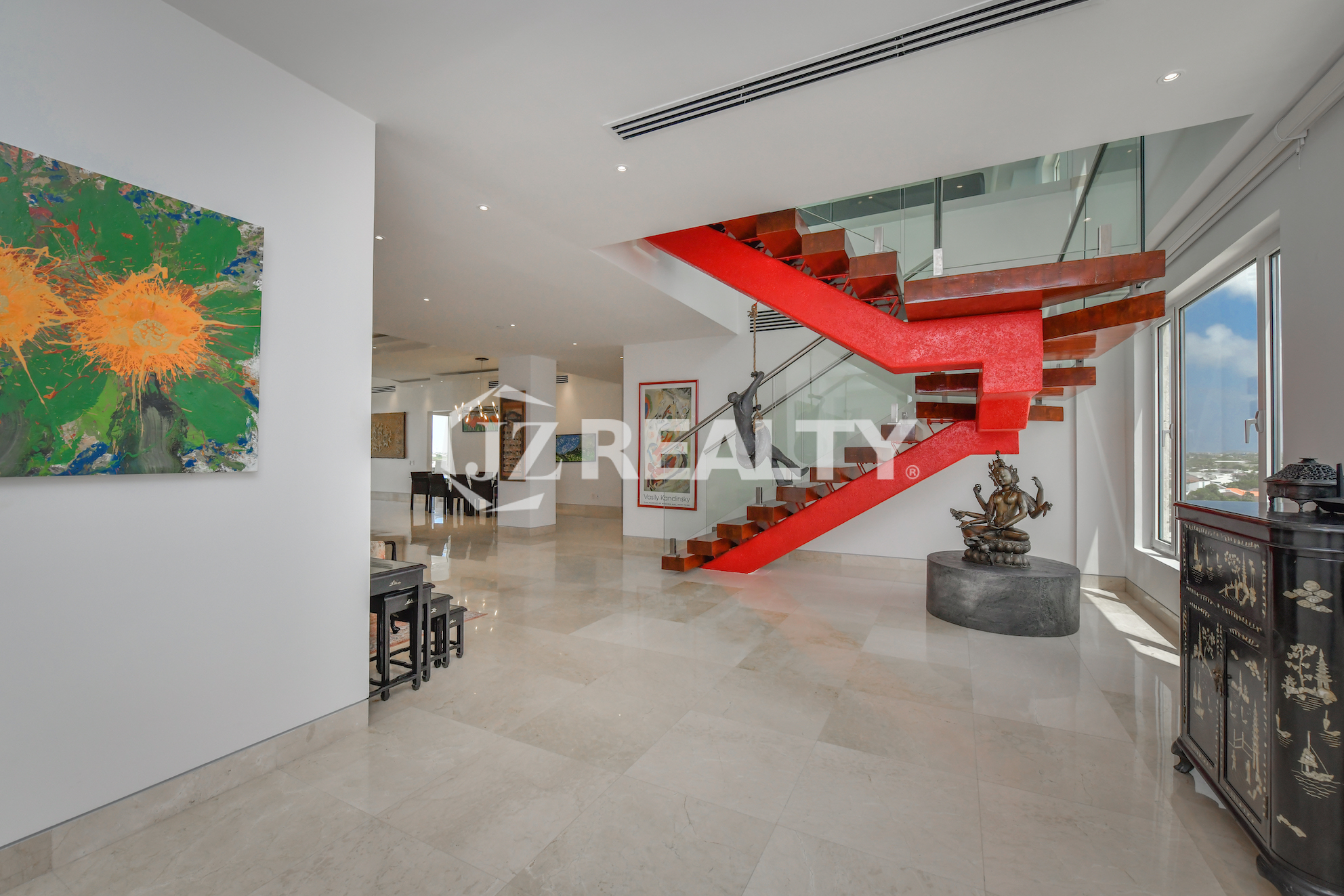 Elegant floating staircase with glass railings and a bold red accent at Coral Shell Penthouse B, Aruba.