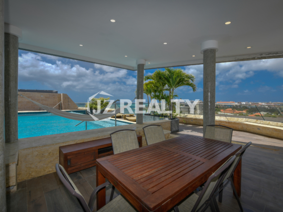 Private poolside dining area at Coral Shell Penthouse B, with scenic views of Aruba’s skyline and coastline.