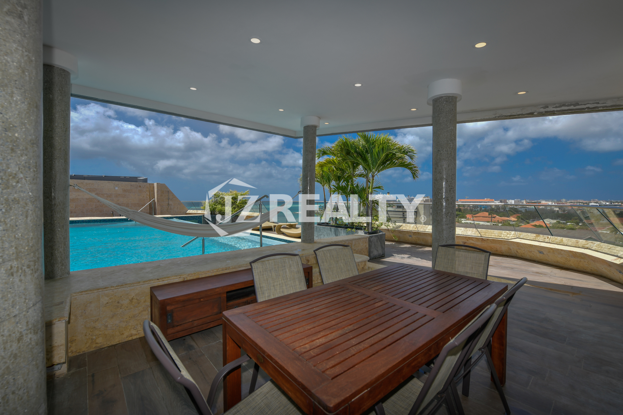 Private poolside dining area at Coral Shell Penthouse B, with scenic views of Aruba’s skyline and coastline.