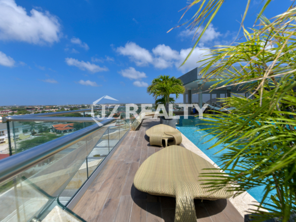 Luxurious sundeck with lounge chairs overlooking Aruba’s coastline at Coral Shell Oceanfront Penthouse B.