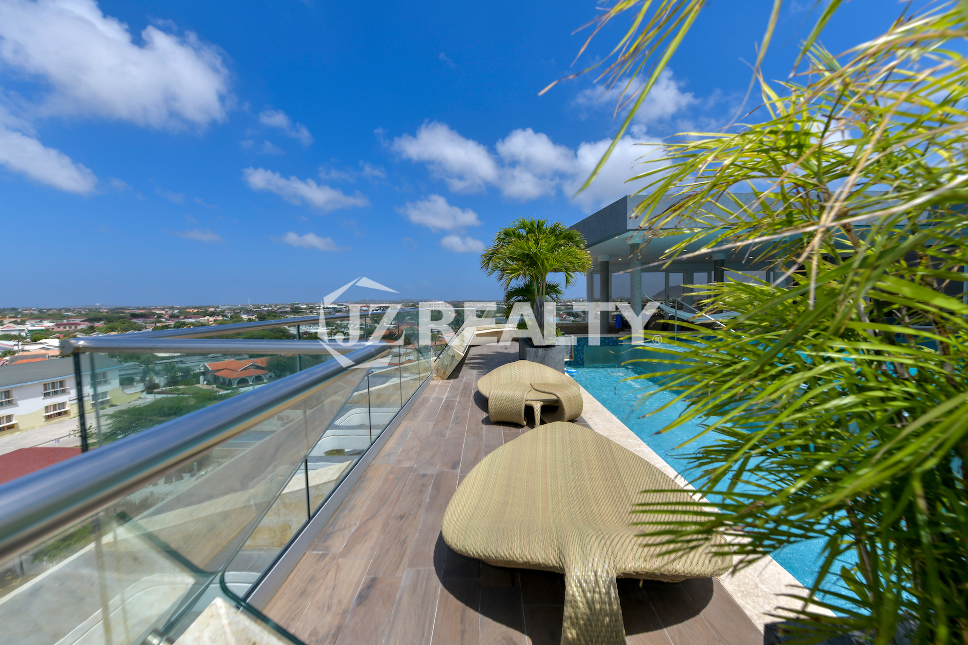 Luxurious sundeck with lounge chairs overlooking Aruba’s coastline at Coral Shell Oceanfront Penthouse B.
